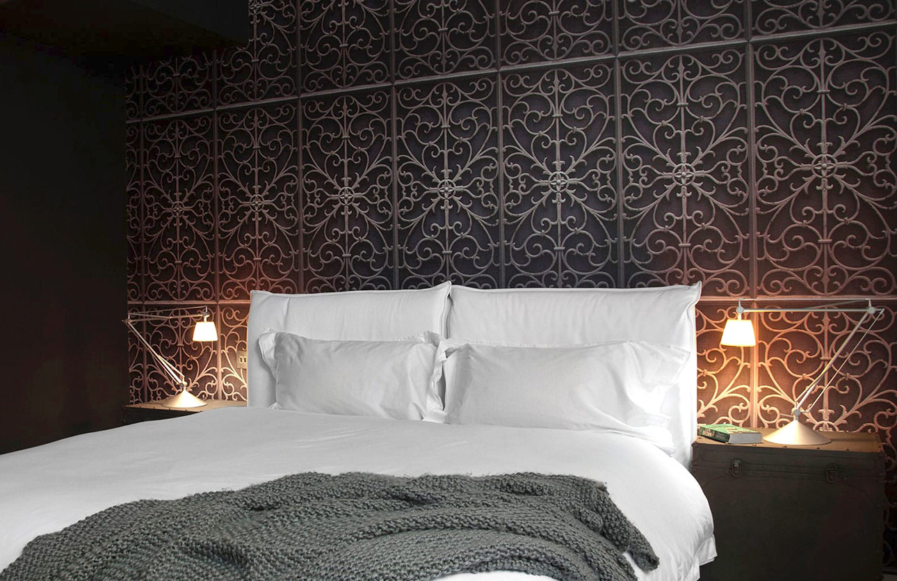 Contemporary bedroom with ornate dark feature wall, white bed linens and grey throw blanket in Soho residence