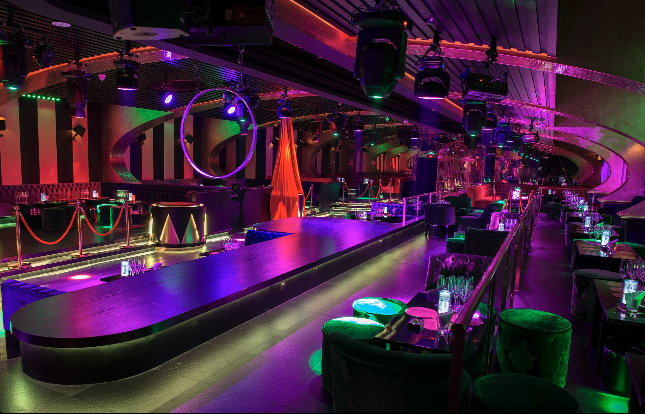 Nightclub runway stage with neon purple and green lighting and circular hoops overhead