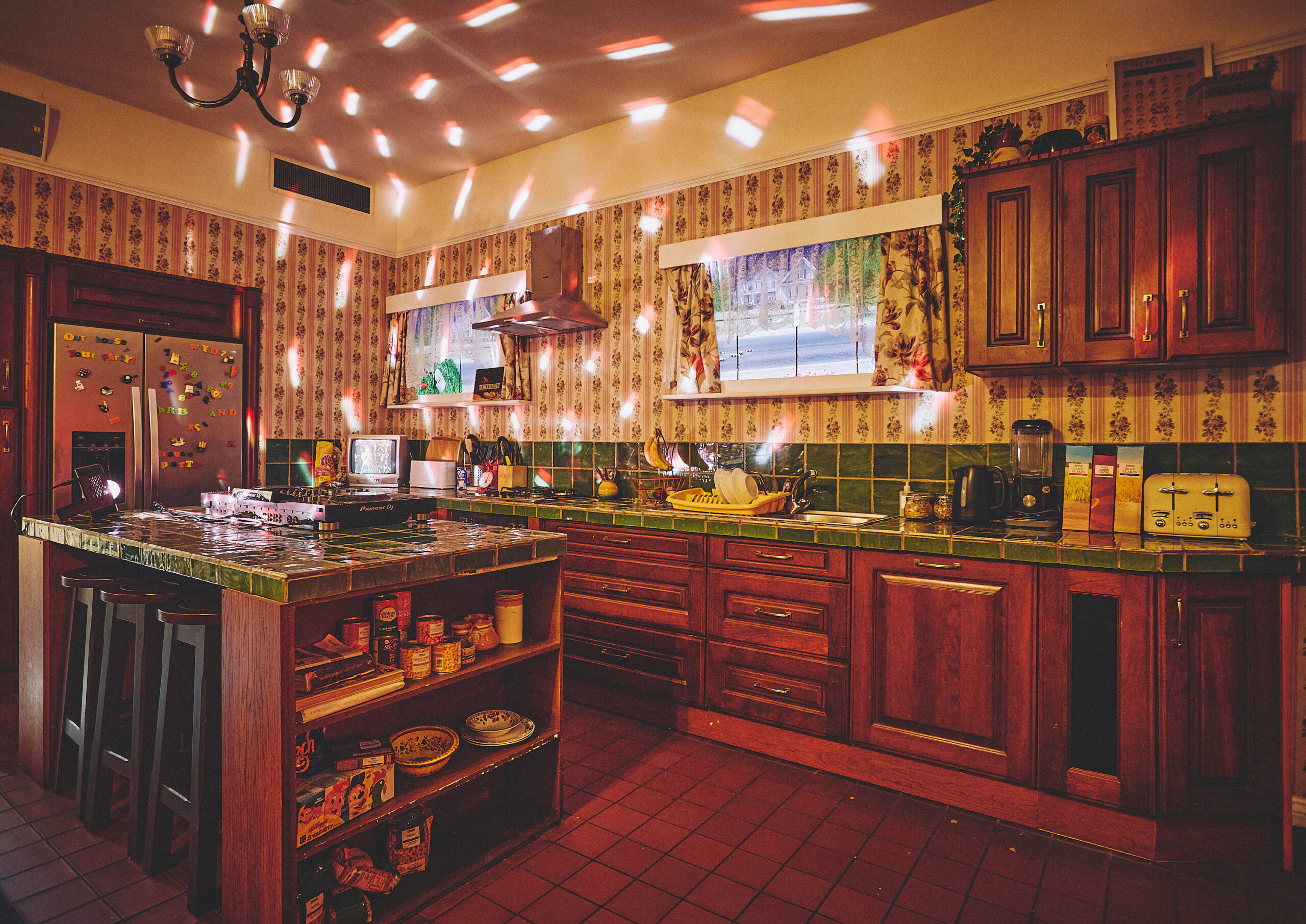 Retro kitchen at House Party Soho with green tile countertops, wooden cabinets and disco lighting