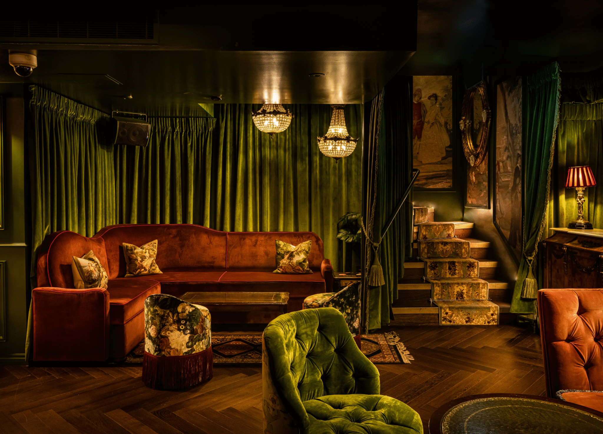 Luxury bar interior with green velvet curtains, ambient lighting, red sofa and armchairs